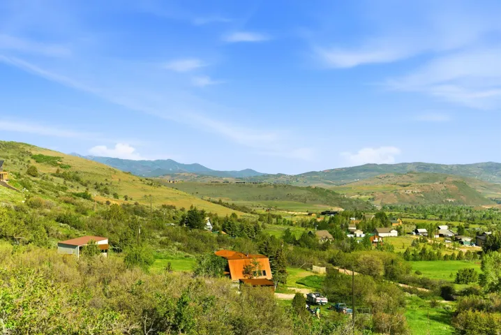 Expansive hillside setting with abundant natural vegetation and distant mountain ranges