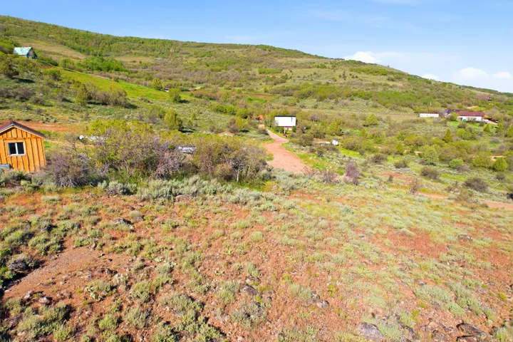 Expansive hillside lot featuring a rustic wood-sided cabin with white-framed windows and a dark roof