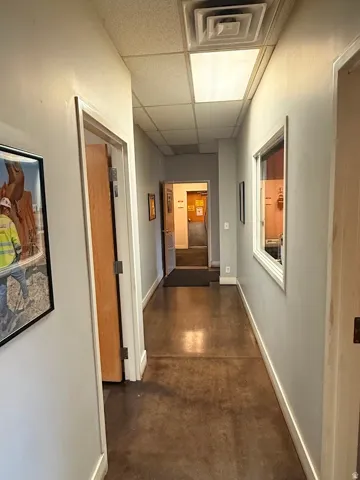 Corridor featuring stained concrete flooring, recessed lighting, drop ceiling, and multiple doorways
