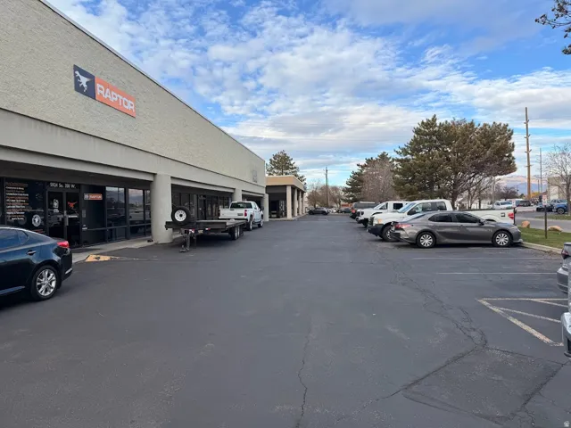Commercial building with a stucco exterior, expansive paved parking lot, and large storefront windows