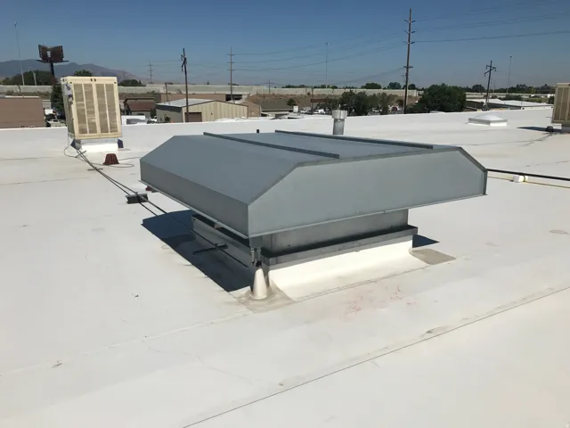 White flat roof with integrated mechanical systems, including a large ventilation unit and an evaporative cooler