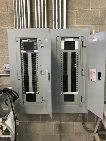 Dual electrical panels with exposed conduit against a block wall