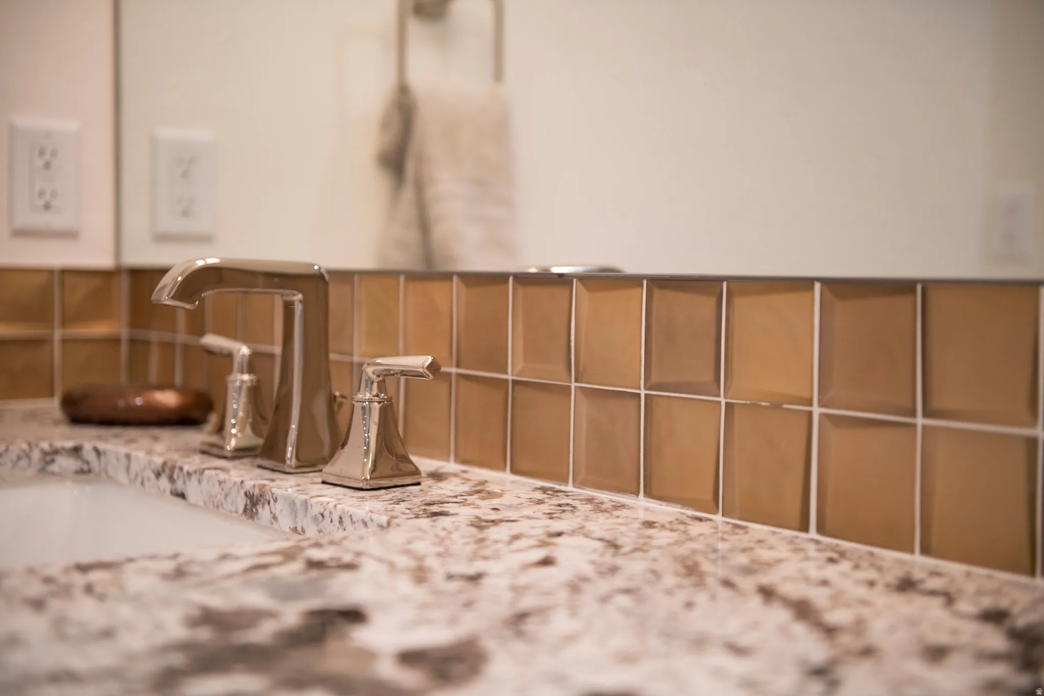 Polished chrome faucet with dual handles, set within a speckled countertop