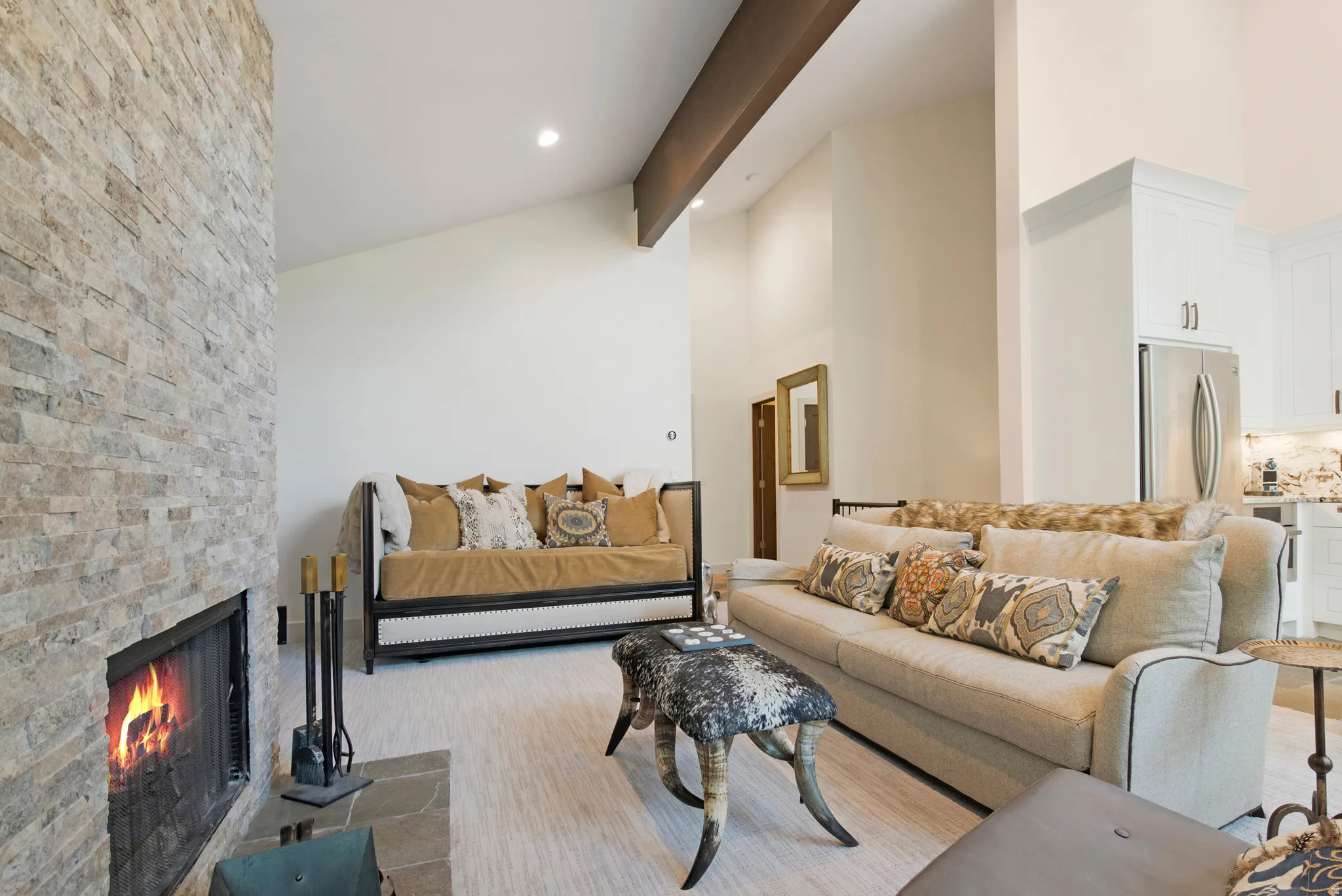 Stone-clad fireplace with slate hearth, vaulted ceilings, and exposed wood beam
