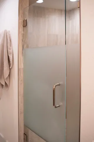 Frosted glass shower enclosure featuring polished chrome hardware, full-height tile surround, and recessed overhead lighting