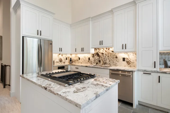 White cabinetry with black hardware, stainless steel appliances, and a gas cooktop on a central island
