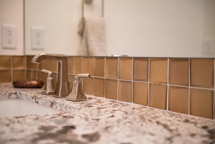Polished chrome faucet with dual handles, set within a speckled countertop