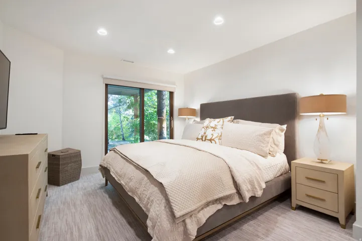Bedroom featuring light-toned walls, recessed lighting, and a sliding glass door providing natural illumination