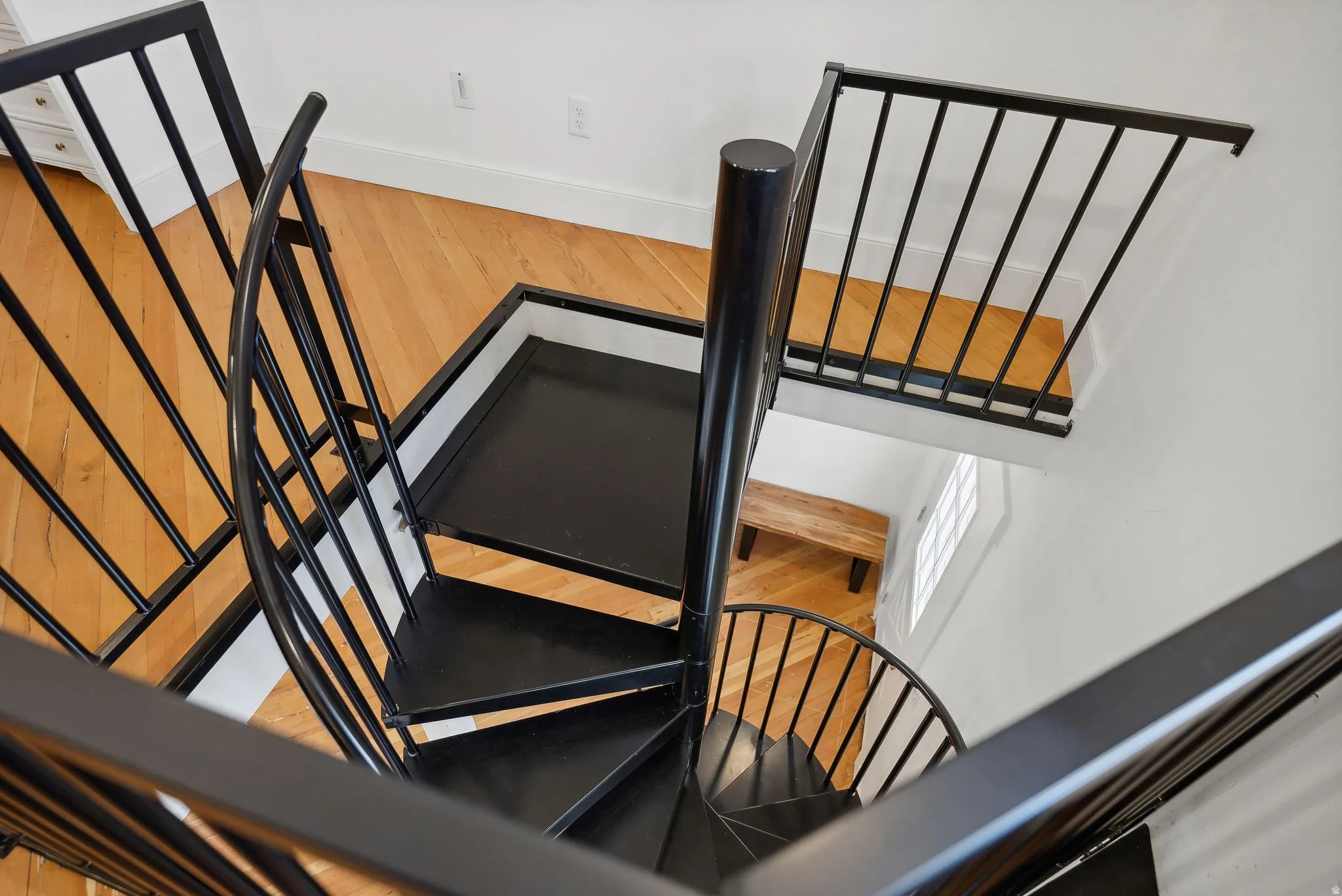 Black spiral staircase featuring metal railings, solid treads, and a central support column