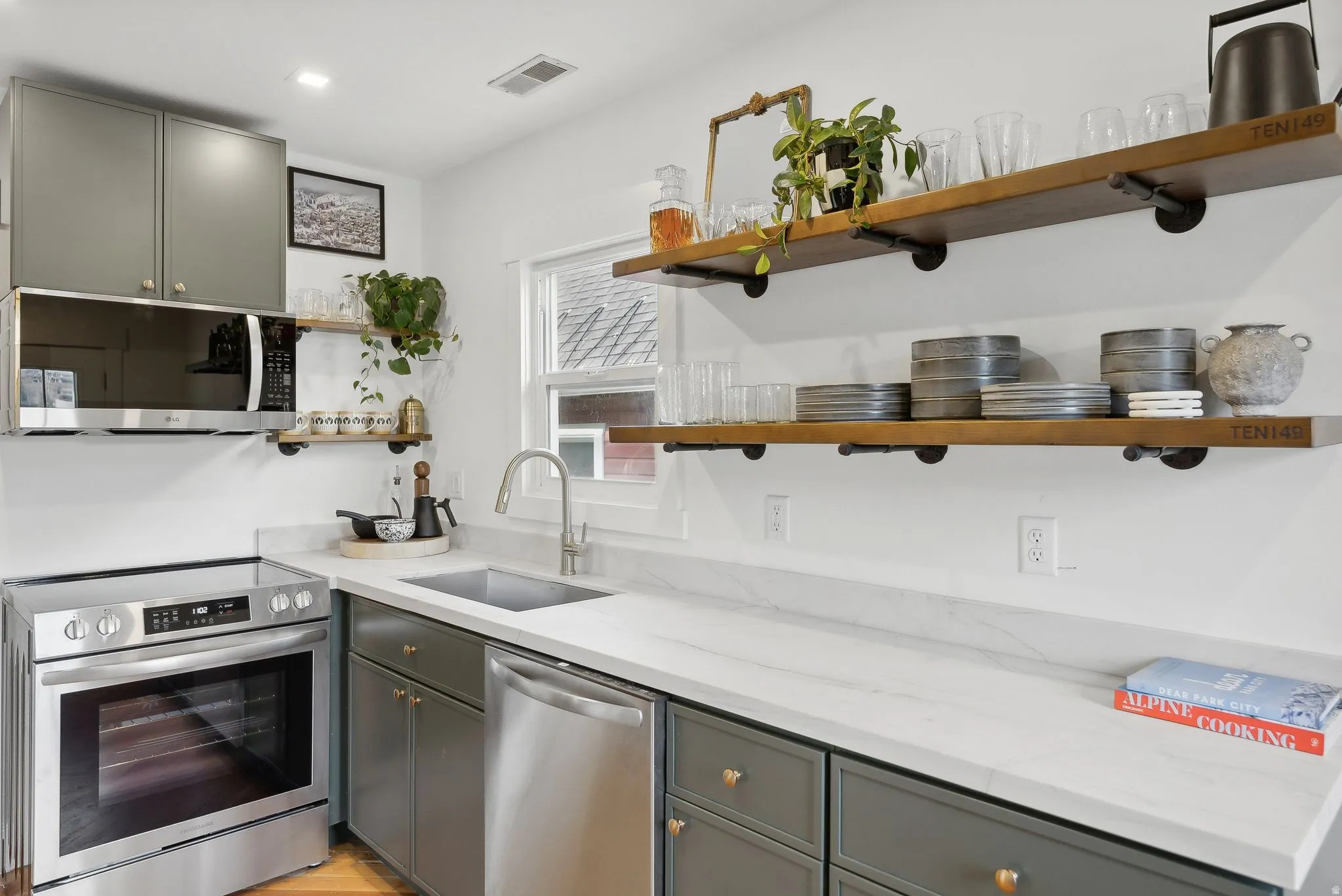 Kitchen featuring stainless steel appliances, open wood-finish shelving, gray cabinetry, and light countertops