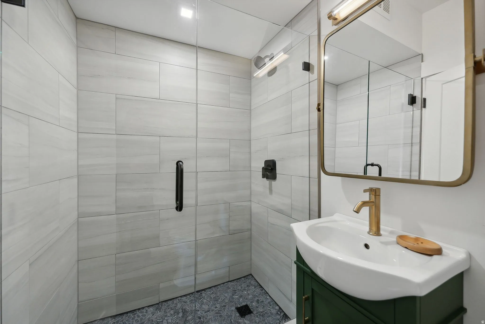Bathroom featuring a glass-enclosed shower with large format tile, a dark gray tiled shower floor, and matte black shower fixtures
