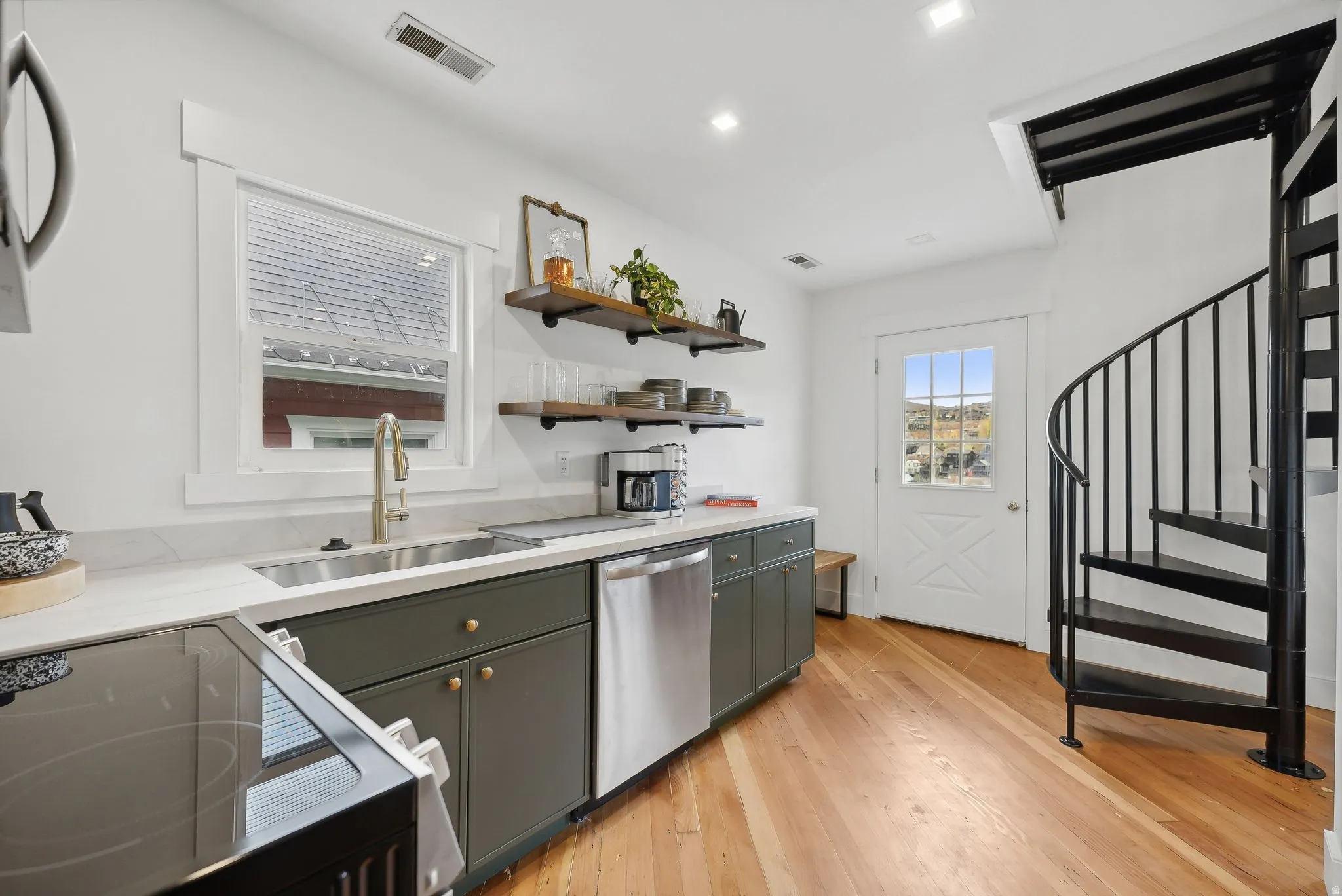 Kitchenette featuring a black metal spiral staircase, wood-finish flooring, and a white paneled door with glass inserts