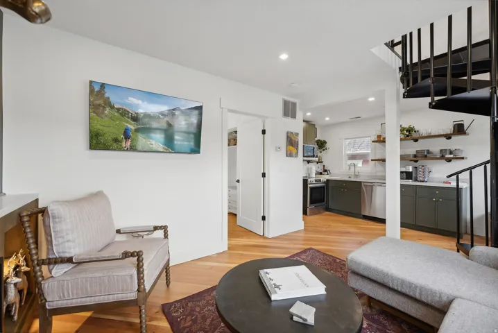 Open-concept living area featuring wood-finish flooring, recessed lighting, and a black spiral staircase