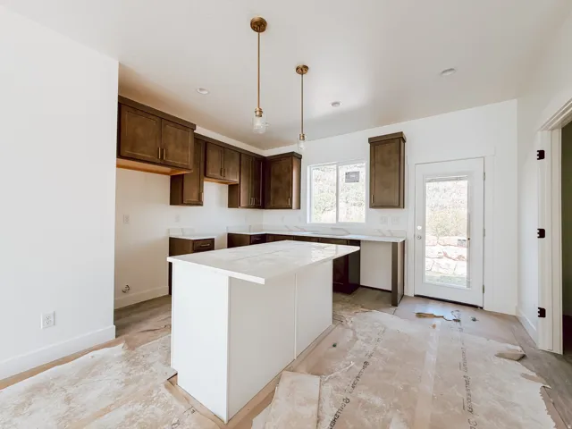 Kitchen featuring dark wood cabinetry, a central island with a solid surface countertop, and pendant lighting