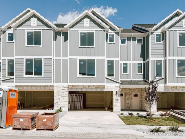 New construction townhome featuring a stone facade, two-car garage, and modern gray siding