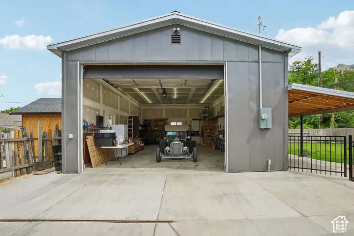 Expansive detached garage featuring a large roll-up door, corrugated metal siding, and a concrete driveway