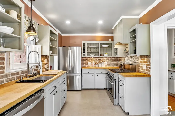 Kitchen featuring butcher block countertops, light gray cabinetry, stainless steel appliances, a brick-style backsplash, and recessed lighting