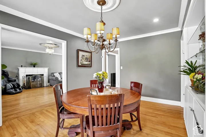 Dining area featuring wood-finish flooring, crown molding, and a chandelier with a decorative ceiling medallion