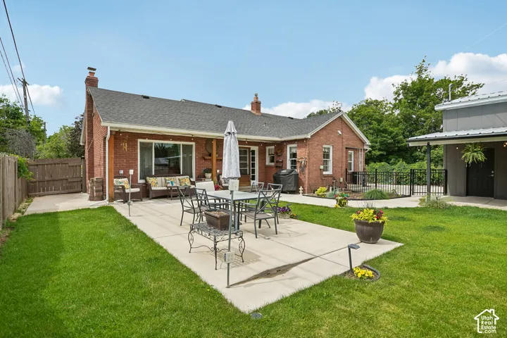 Expansive backyard featuring a large concrete patio, lush green lawn, and a privacy fence