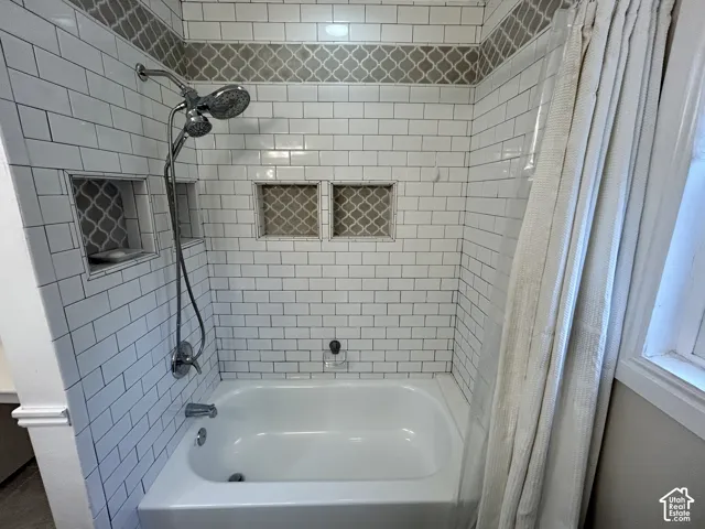 Brand new! Tub and shower combination featuring subway tile surround, decorative accent tile, two recessed niches, and a dual shower head fixture