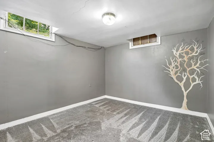 Lower-level room with gray walls, patterned carpet flooring, and a white baseboard trim