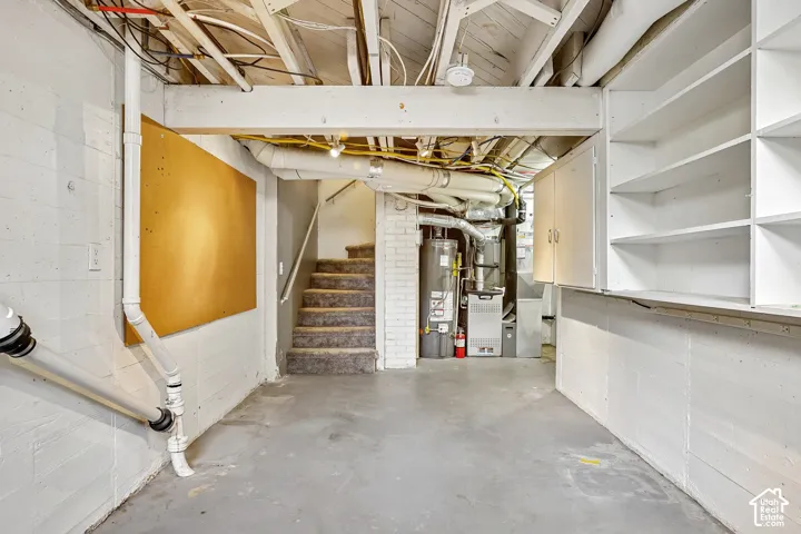 Lower level storage area featuring built-in white cabinetry and open shelving