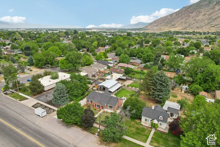 Aerial view showcasing a neighborhood with mature tree coverage and mountainous terrain in the background