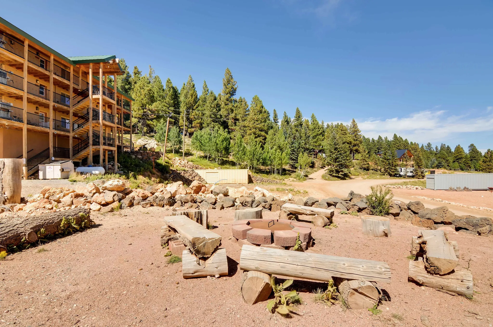 Outdoor gathering area featuring a stone fire pit and log bench seating