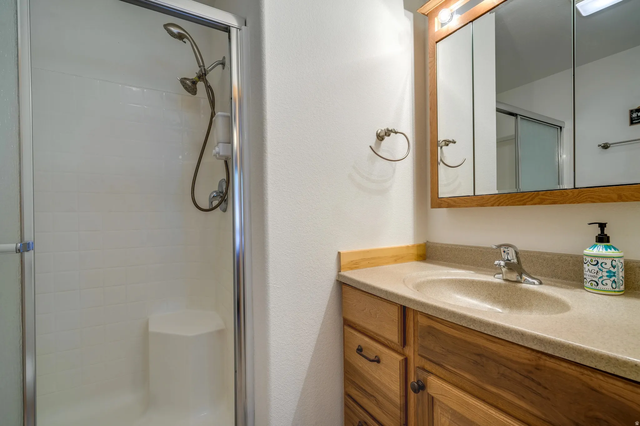 Bathroom featuring a wood-finish vanity with a built-in sink and laminate countertop