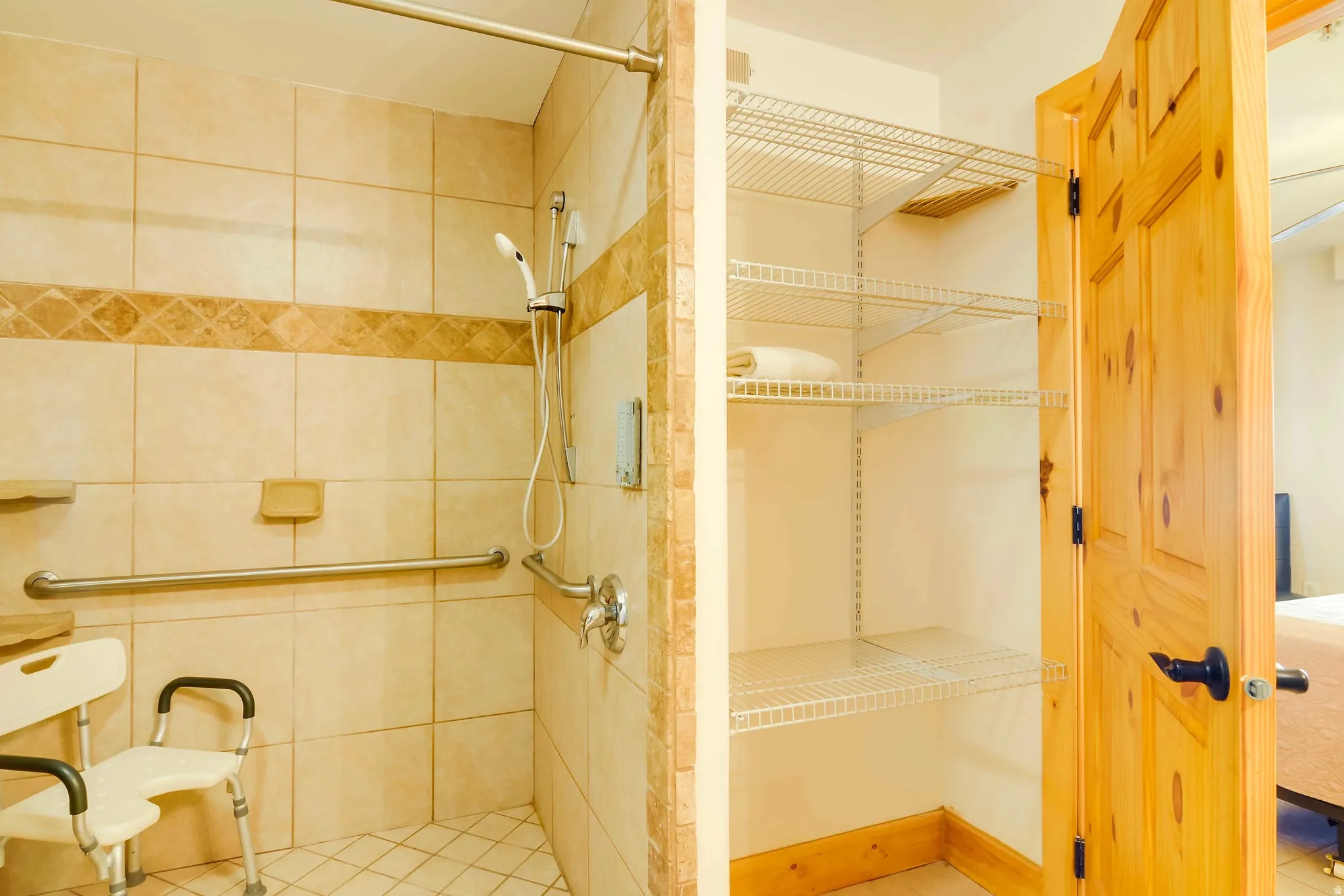 Tiled shower with grab bars and a handheld shower head, featuring a decorative accent tile band