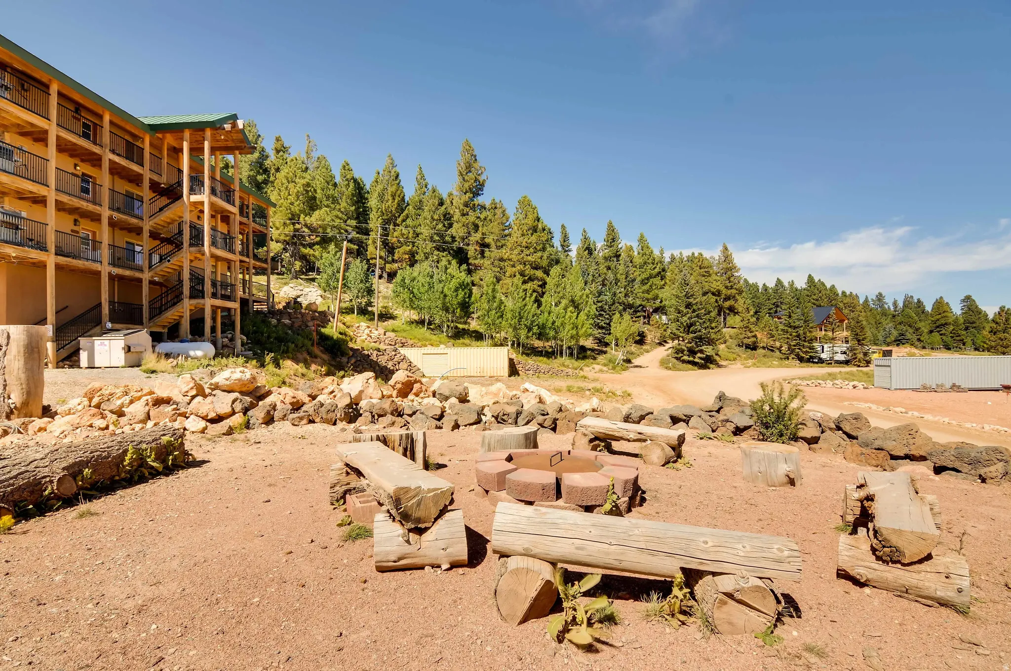 Outdoor gathering area featuring a stone fire pit and log seating