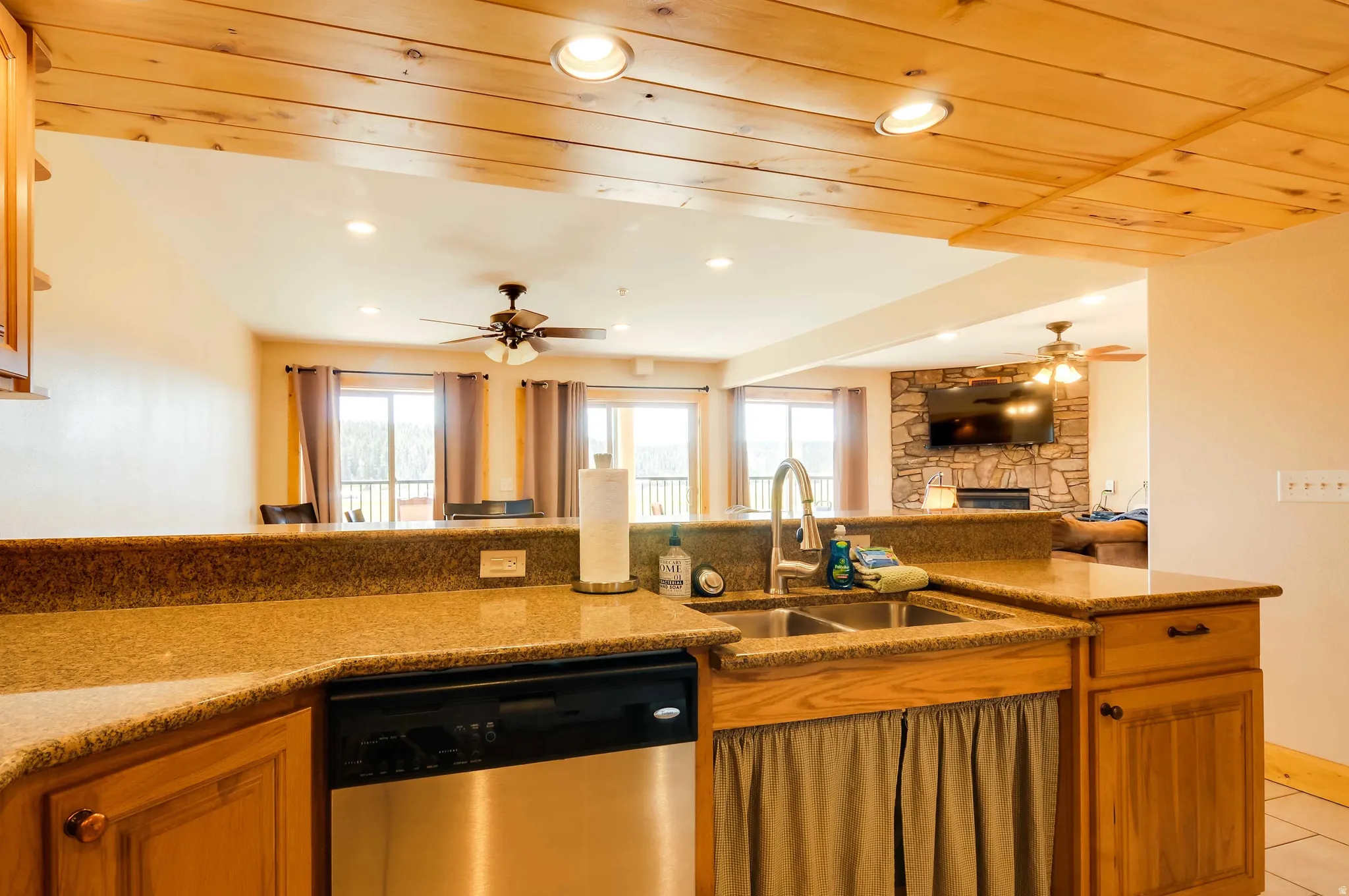 Kitchen with wood cabinetry, granite countertops, stainless steel dishwasher, and a double basin sink