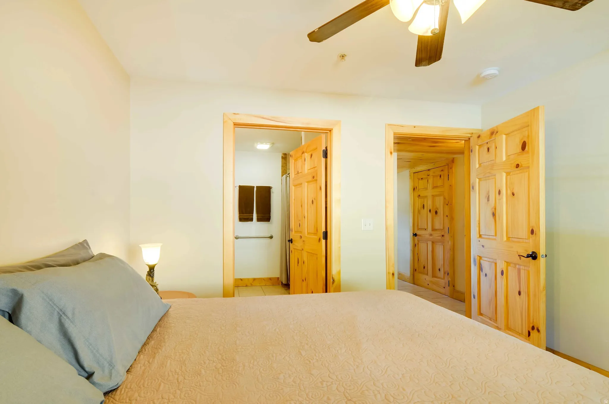 Neutral wall paint, natural wood doors, and a ceiling fan with integrated lighting