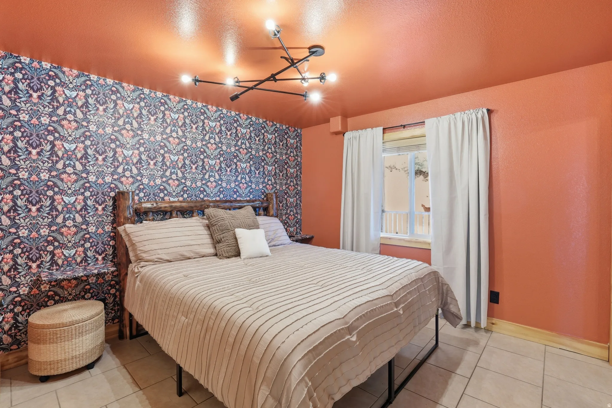Interior room featuring an accent wall with patterned wallpaper, terra cotta-painted walls and ceiling, and a modern multi-bulb light fixture