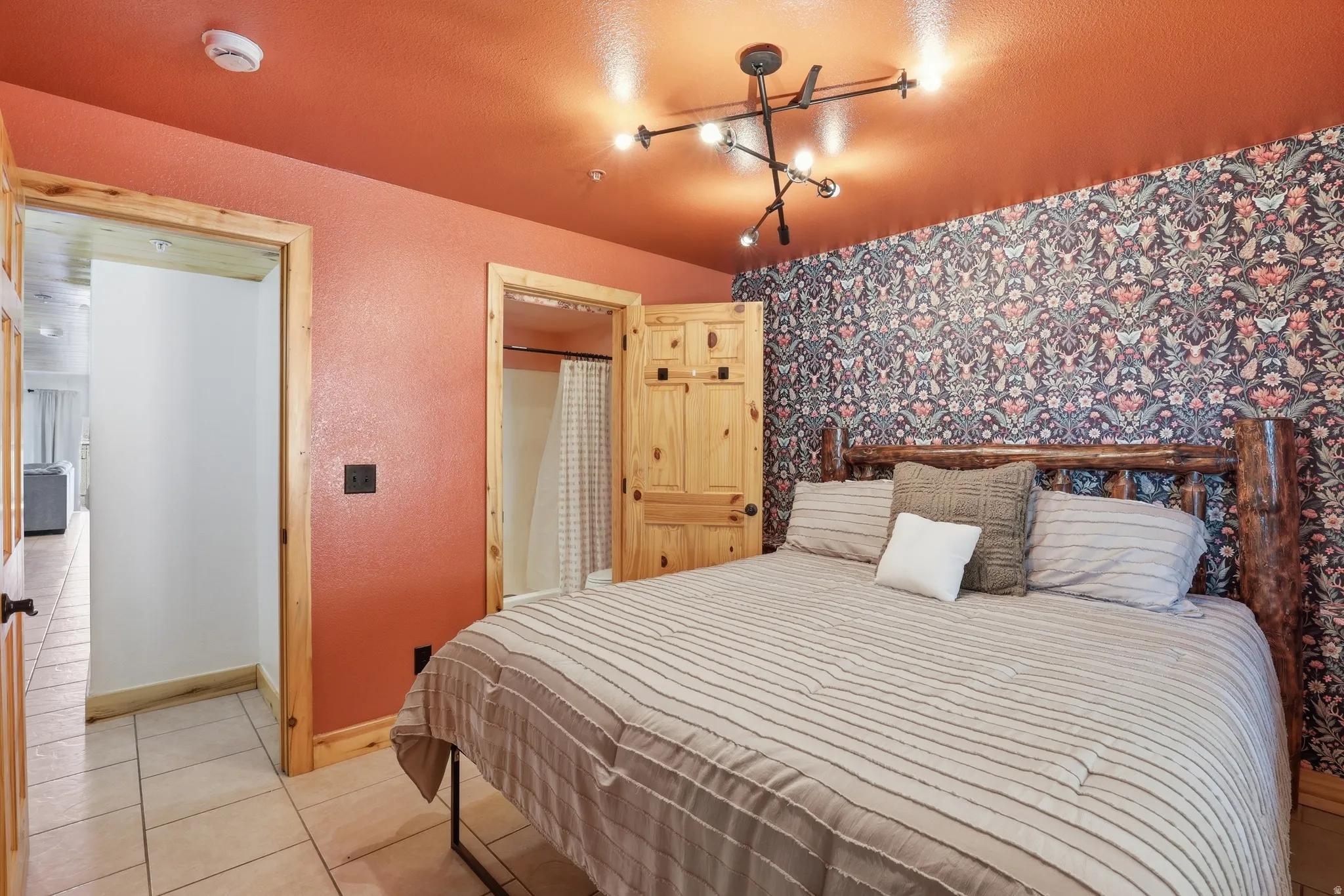 Bedroom featuring an accent wall with botanical-patterned wallpaper