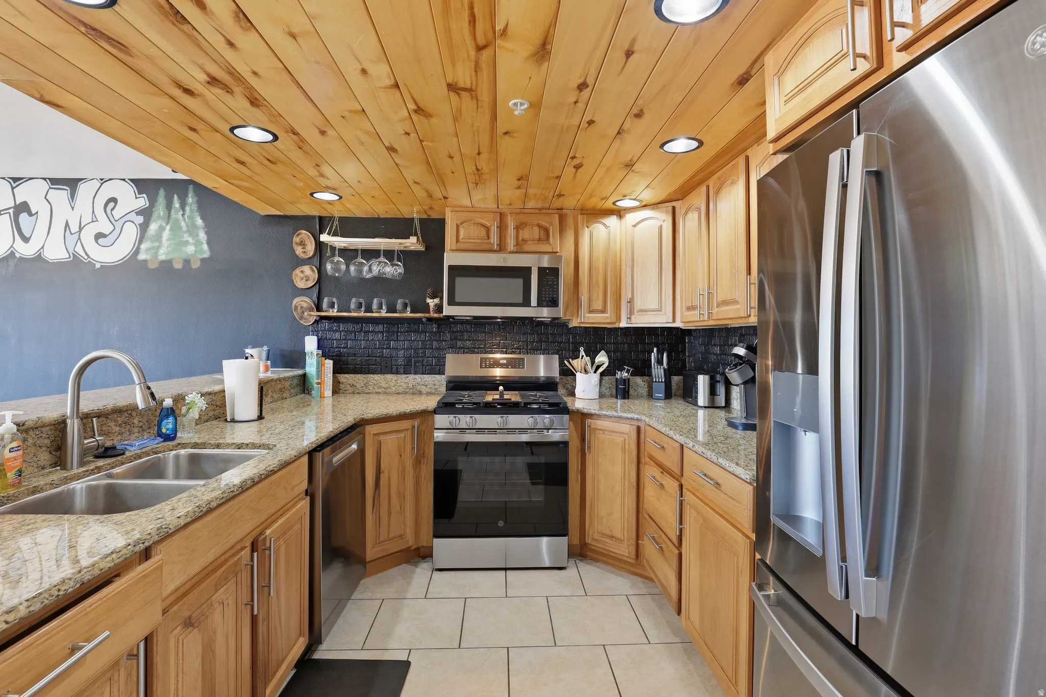 Kitchen featuring a wood-finish ceiling with recessed lighting, wood cabinetry, stainless steel appliances, granite countertops, and a tile backsplash