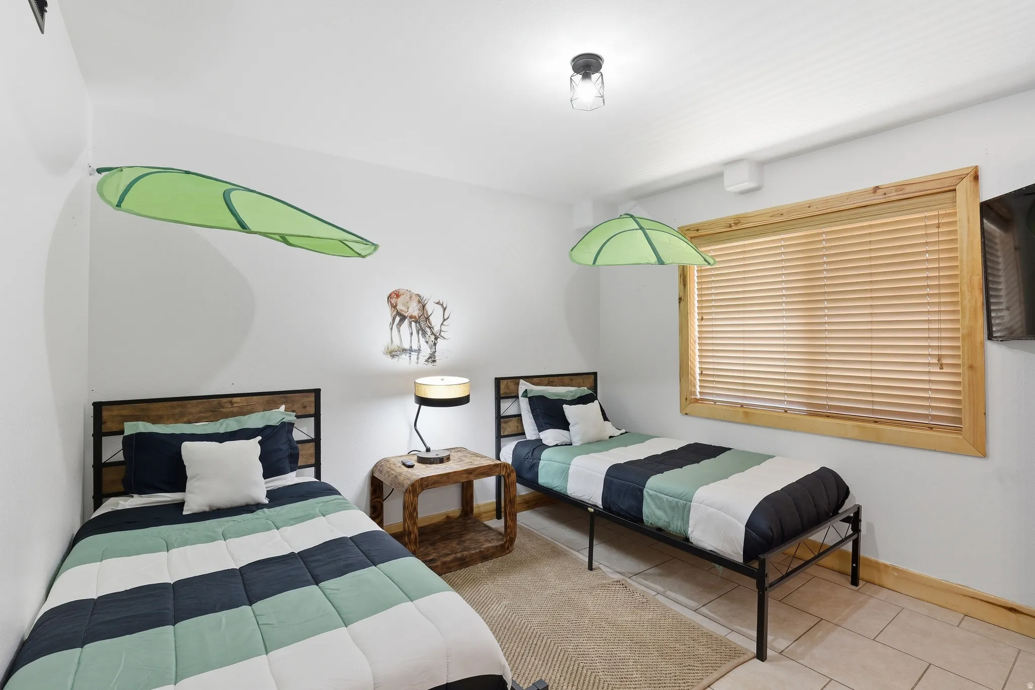 Room featuring neutral wall paint, a natural wood-trimmed window with horizontal blinds, tiled flooring, wood-finish baseboards, and a flush-mount ceiling light fixture