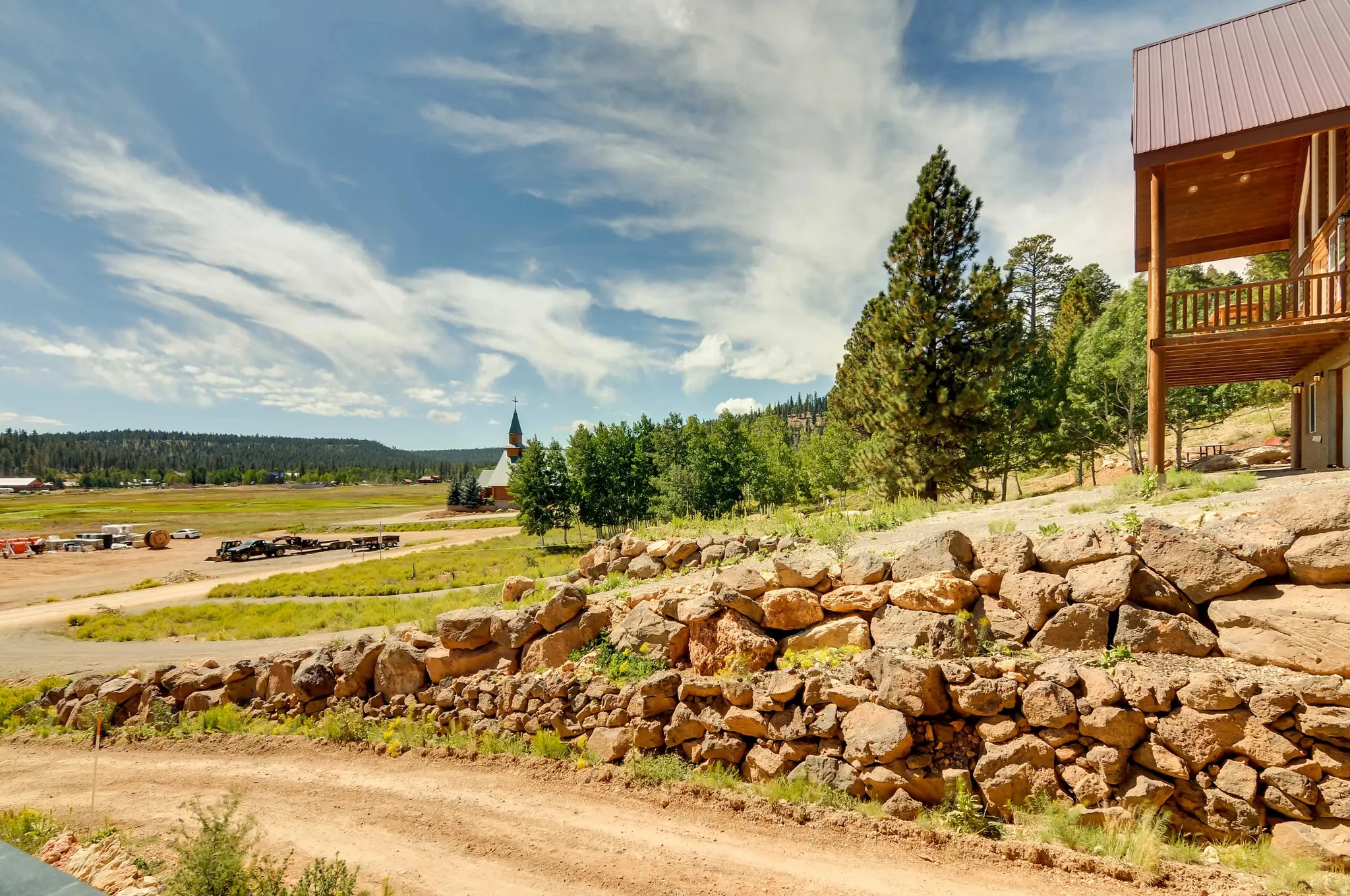 Elevated property with a multi-level rock retaining wall and a dirt access road