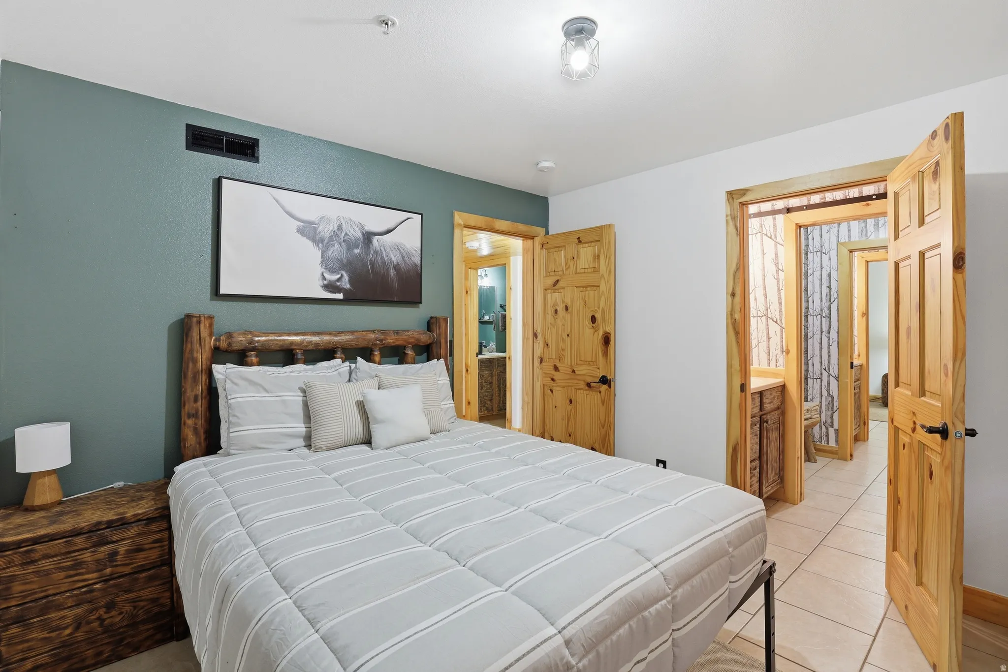 Bedroom featuring a unique wood log bed frame, rustic wood-paneled doors, and an overhead lighting fixture
