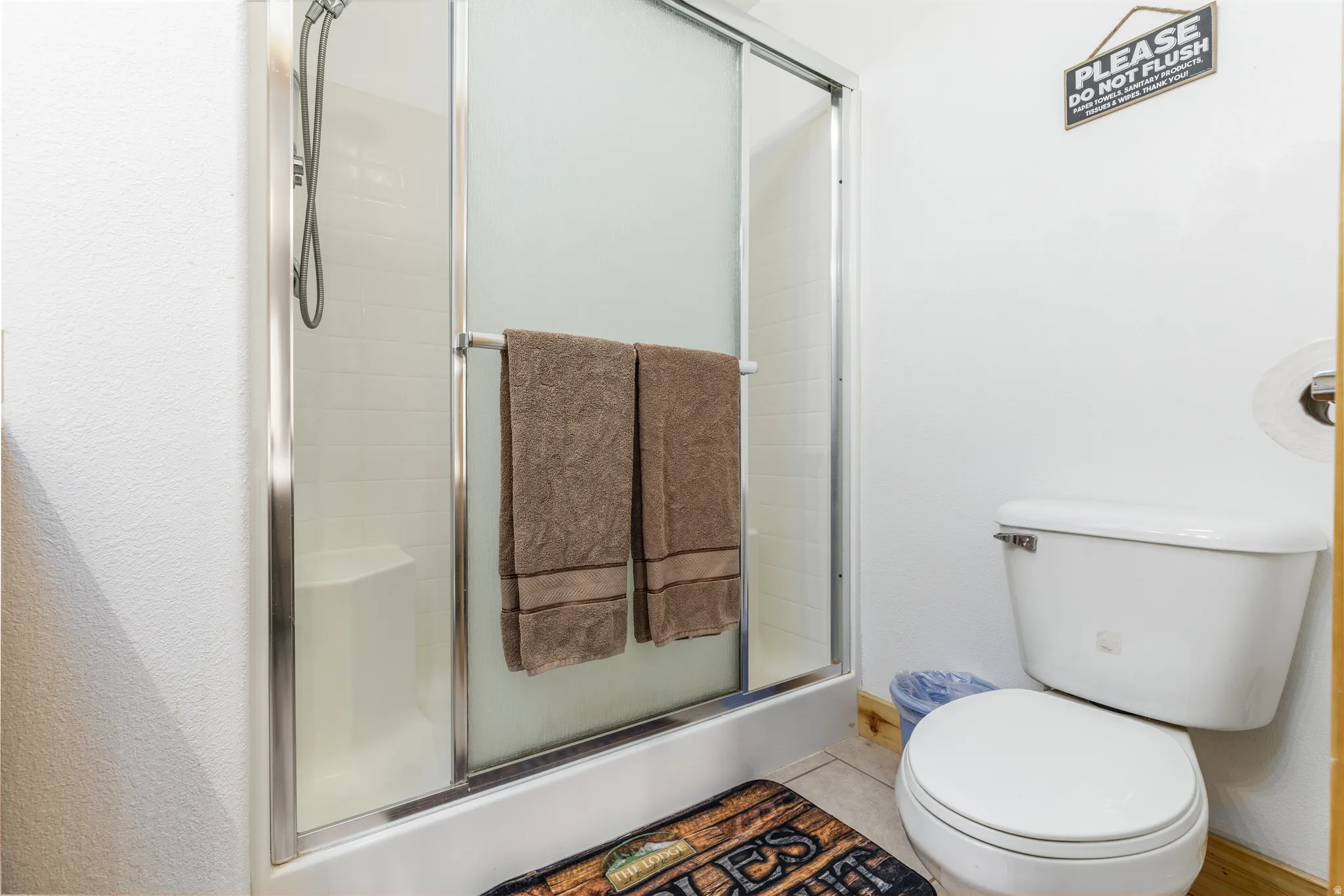 Bathroom featuring a shower with sliding glass doors, white tiled walls, and a built-in shower seat