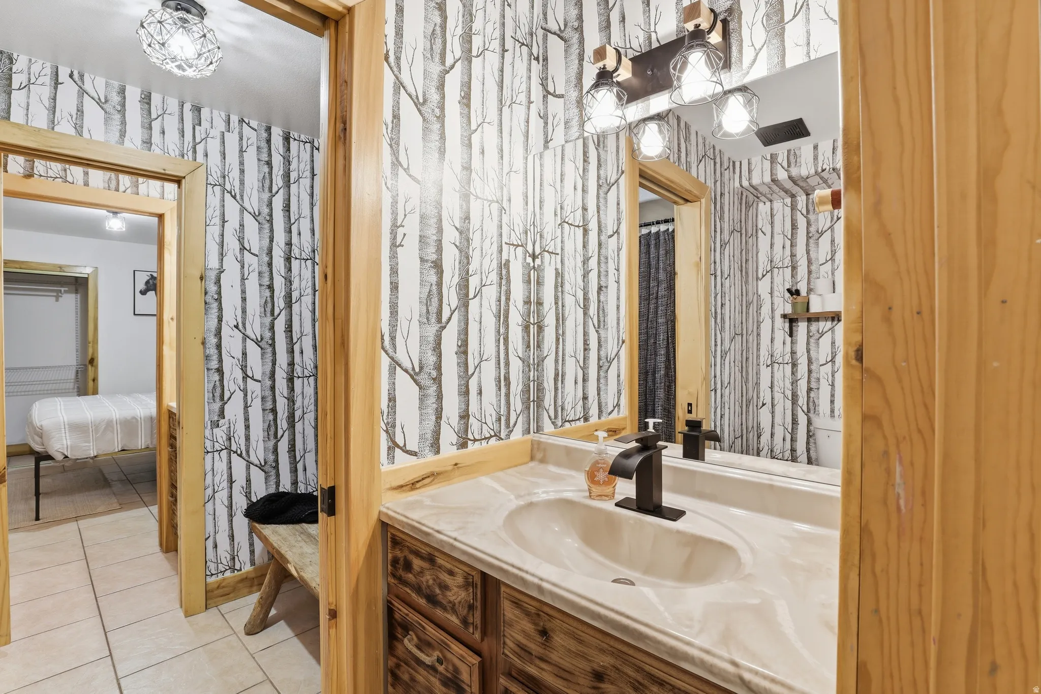 Bathroom vanity featuring a light-toned countertop with integrated sink, a matte black faucet, and a rustic wood-finish cabinet