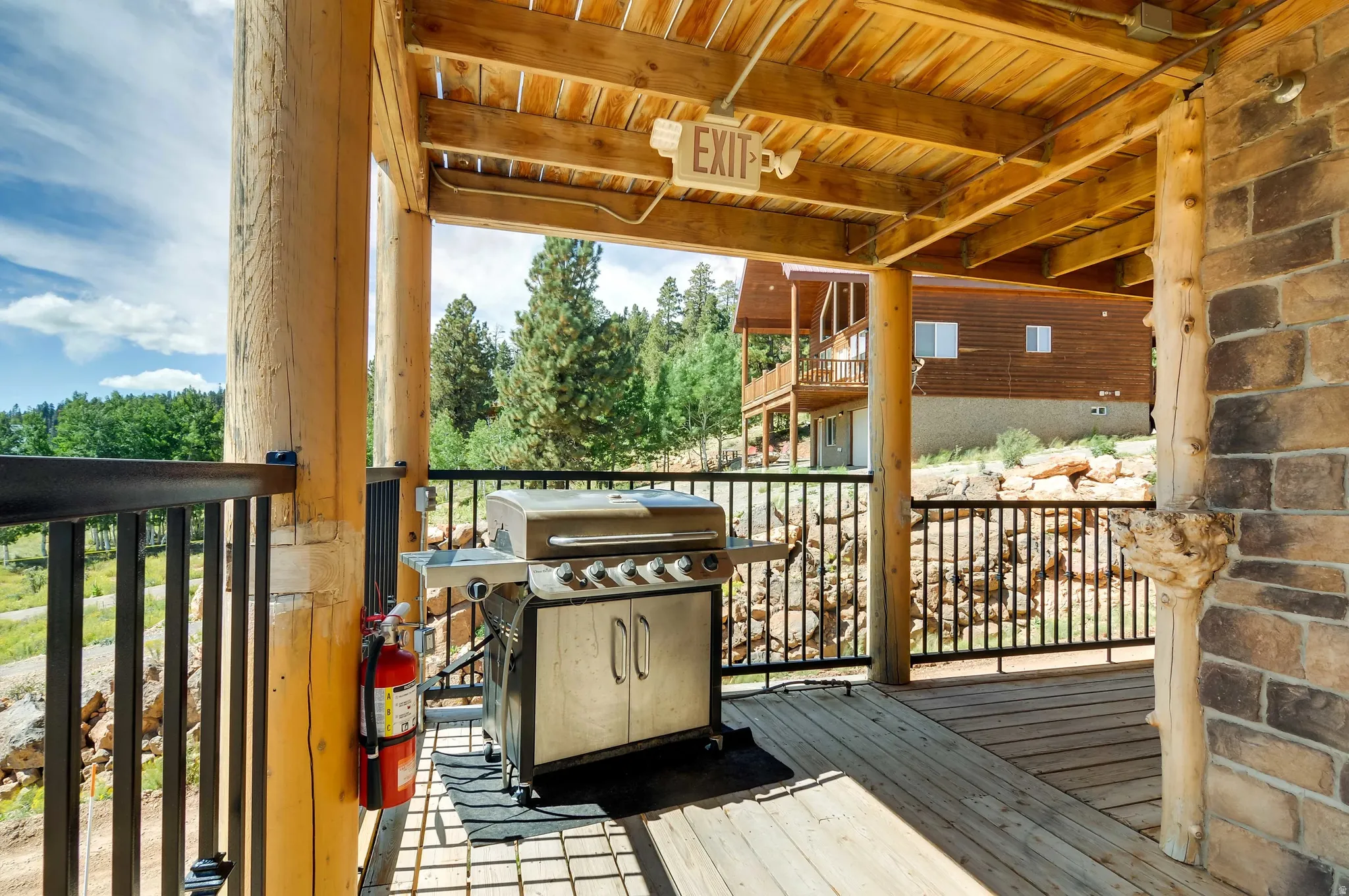 Expansive covered outdoor deck featuring natural wood support columns, wood-finish flooring, and black metal railings