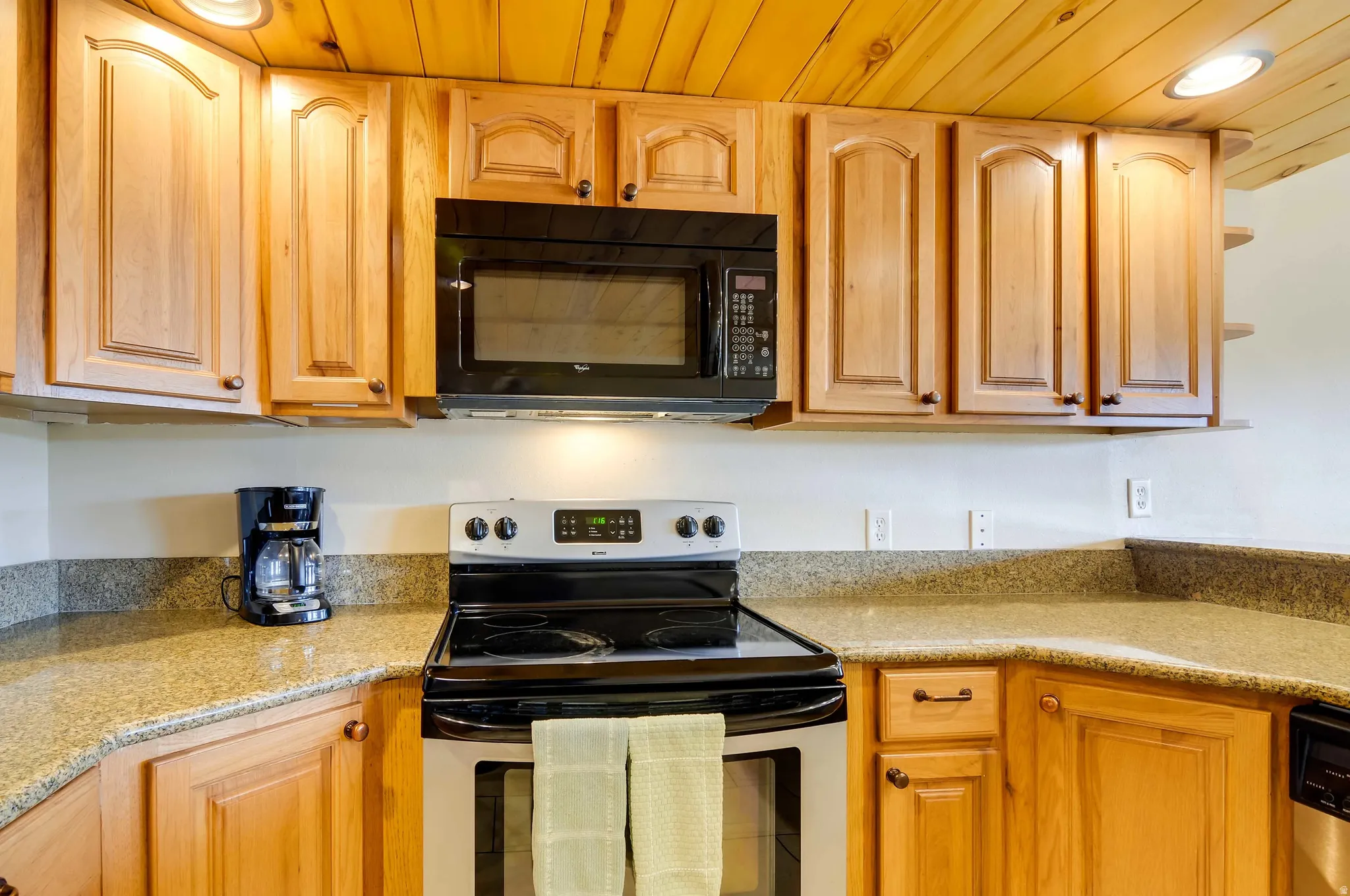 Kitchen featuring wood cabinetry, granite-style countertops, and a black over-the-range microwave