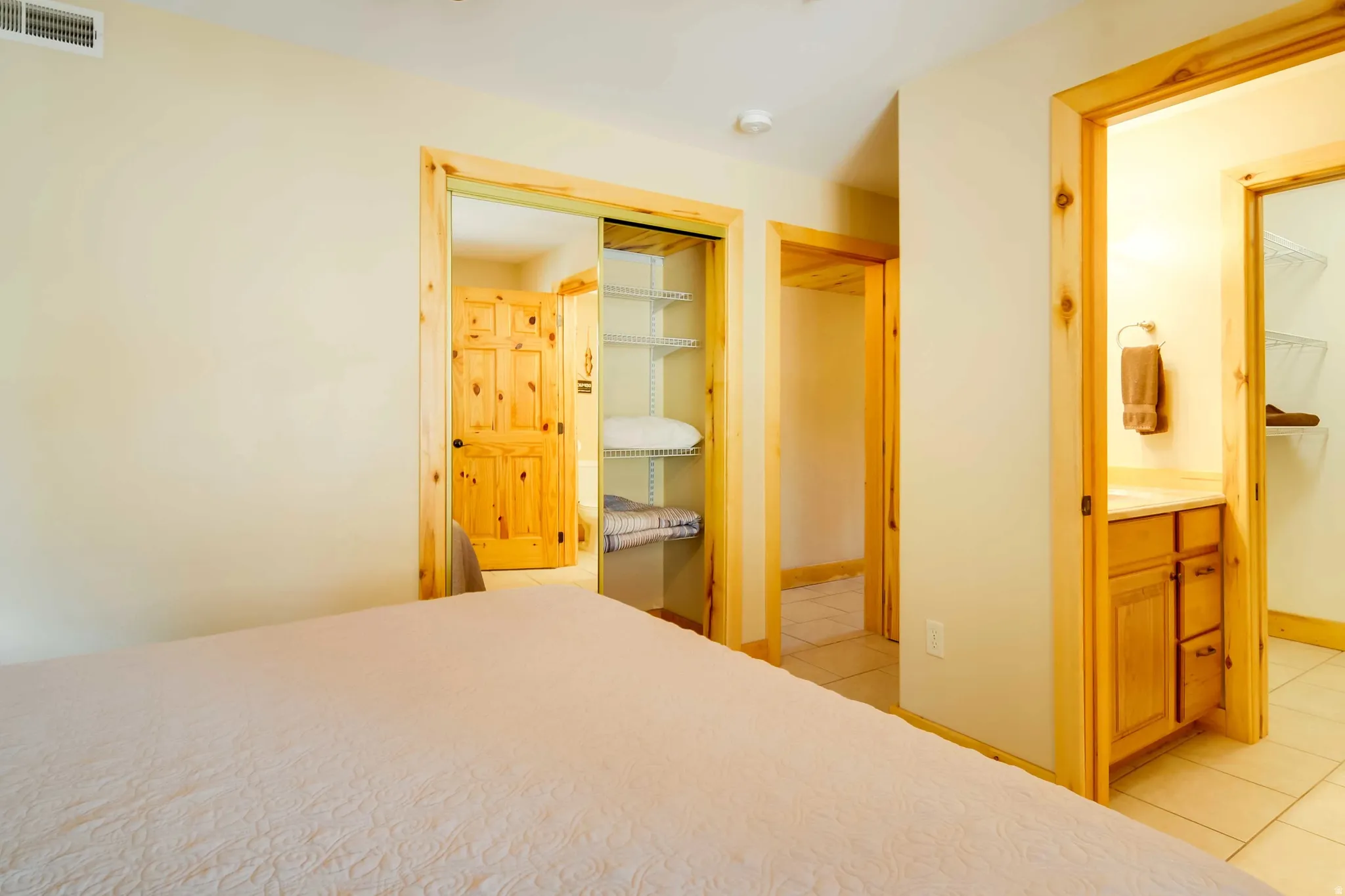 Wood-trim doorways frame a bathroom vanity with a light wood-finish cabinet and a sliding closet with wire shelving