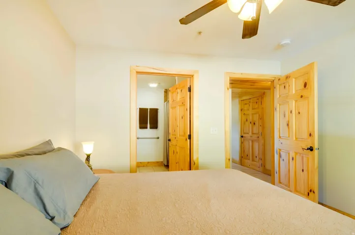 Neutral wall paint, natural wood doors, and a ceiling fan with integrated lighting