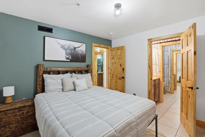 Bedroom featuring a unique wood log bed frame, rustic wood-paneled doors, and an overhead lighting fixture