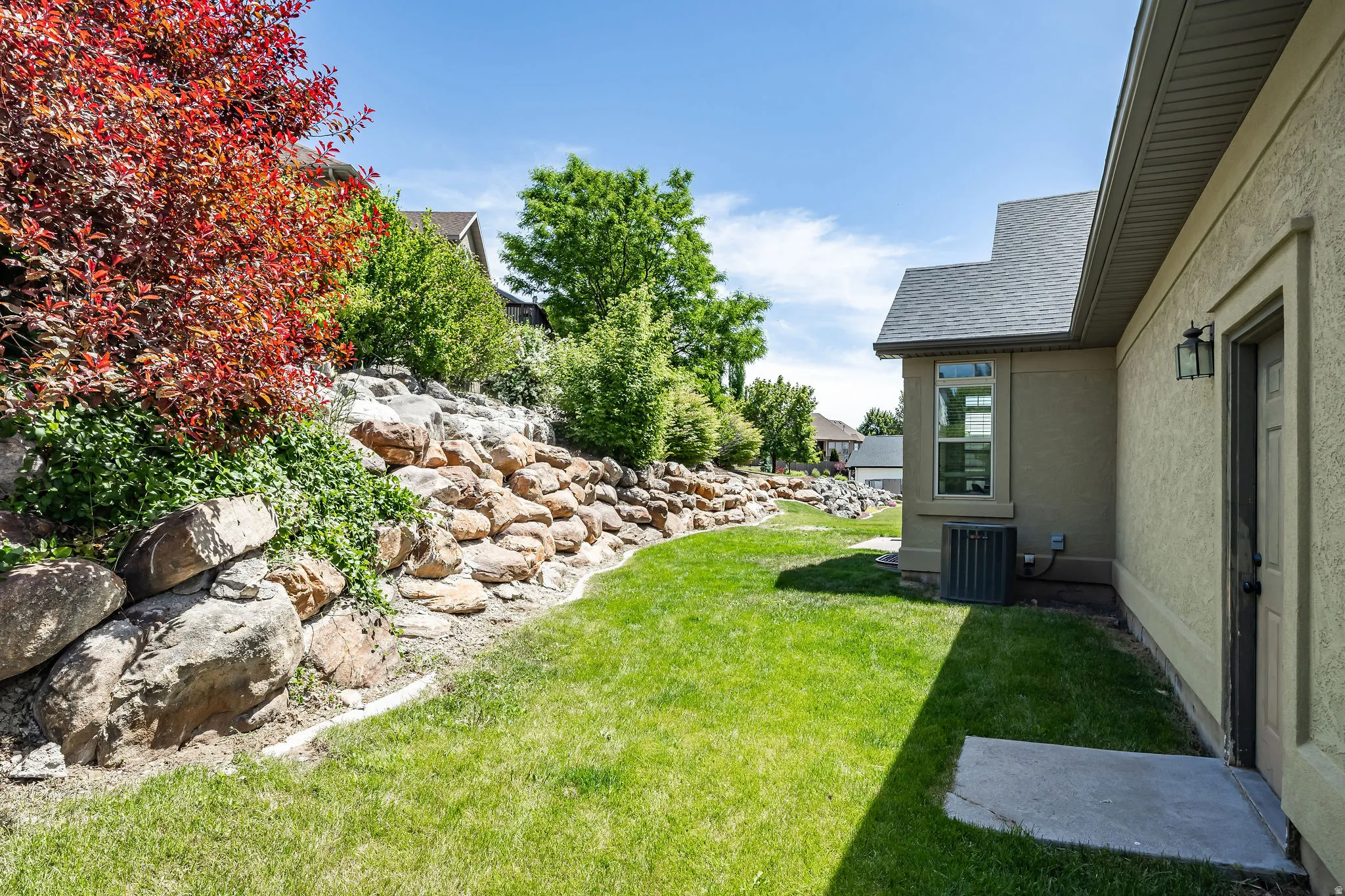 Lush landscaping featuring a stone retaining wall and vibrant foliage