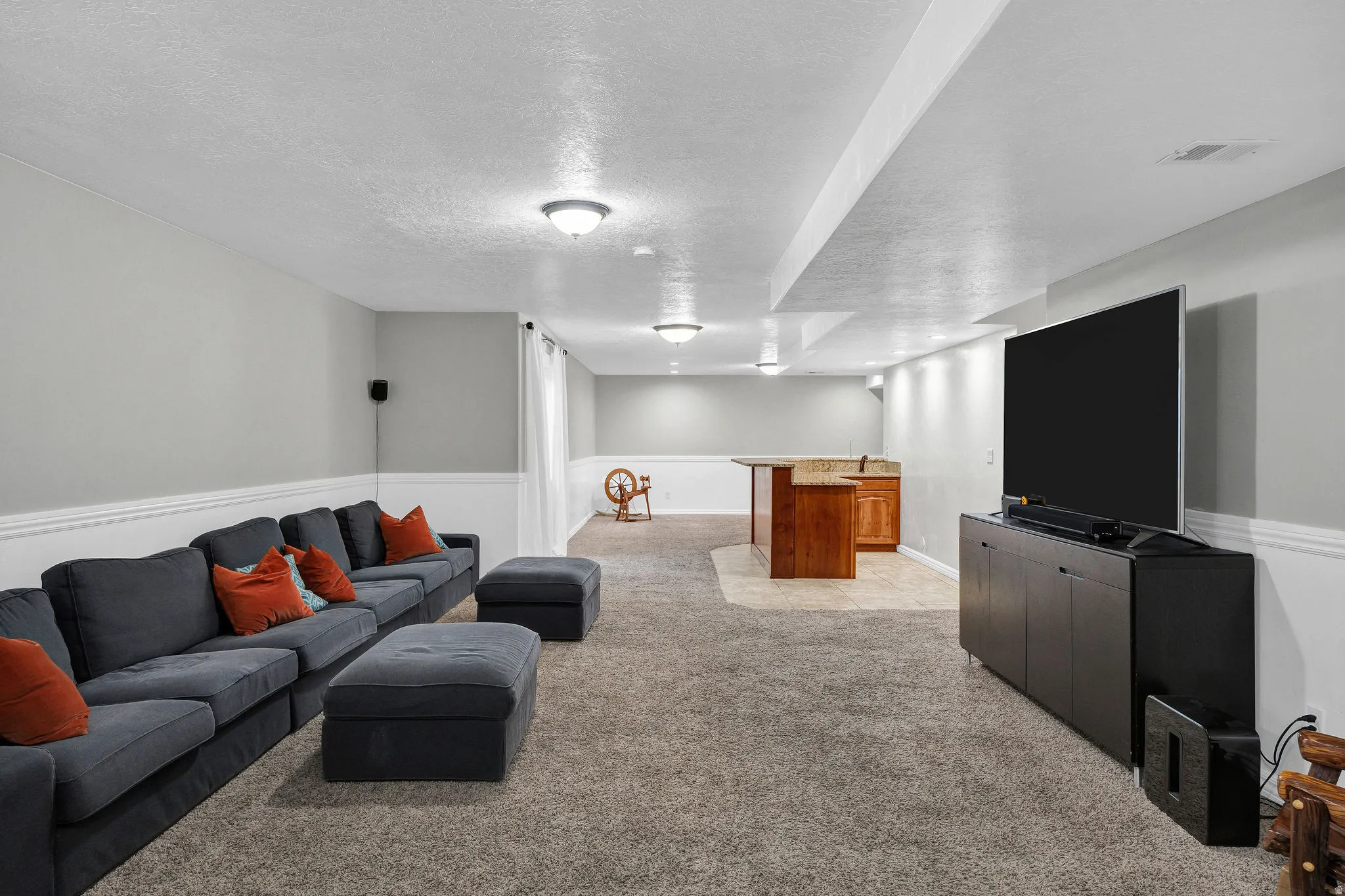 Finished basement featuring plush carpet flooring, recessed lighting, and a built-in wet bar with wood cabinetry and stone countertops