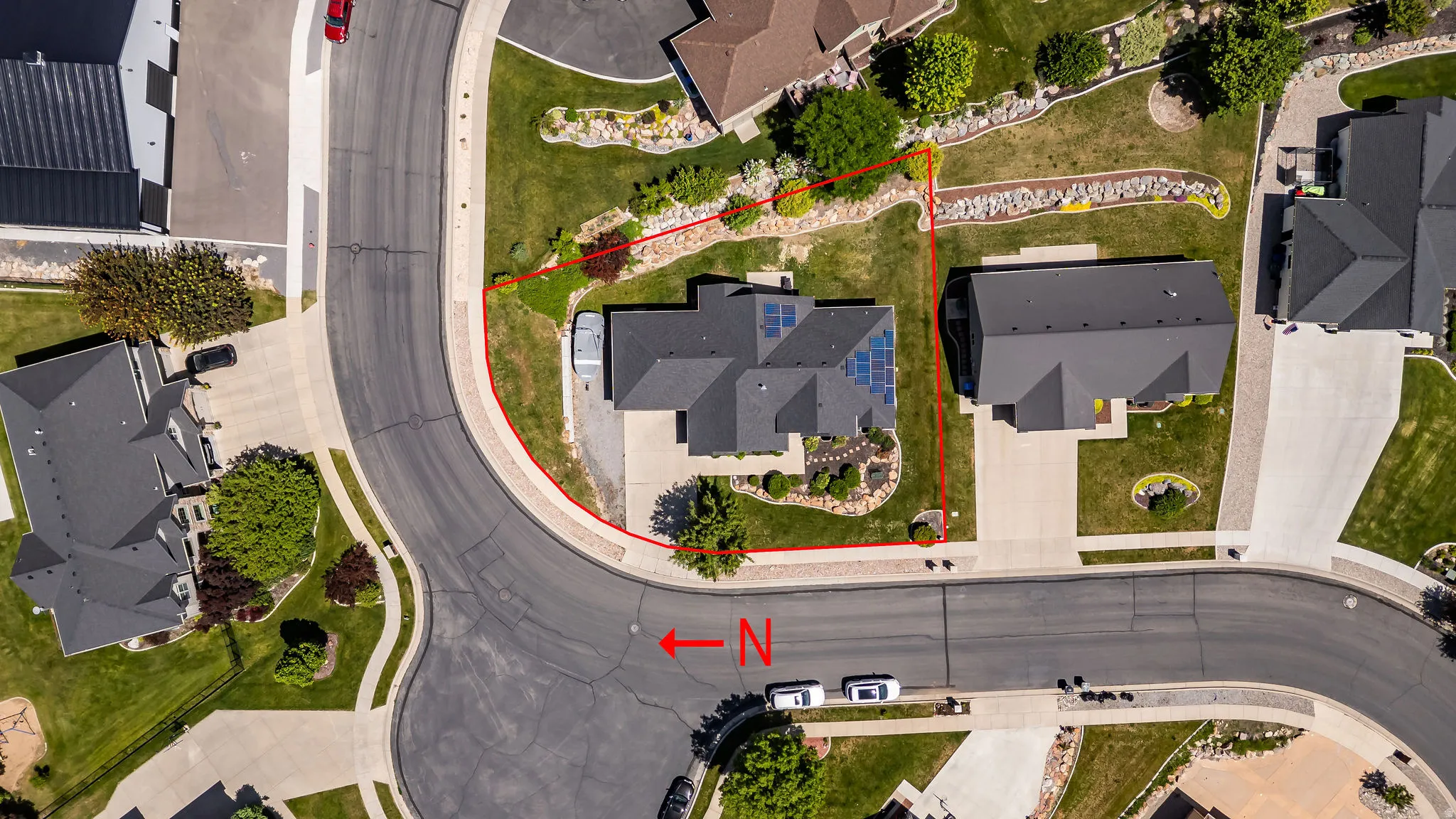 Aerial view showcasing a corner lot with a dark-roofed residence