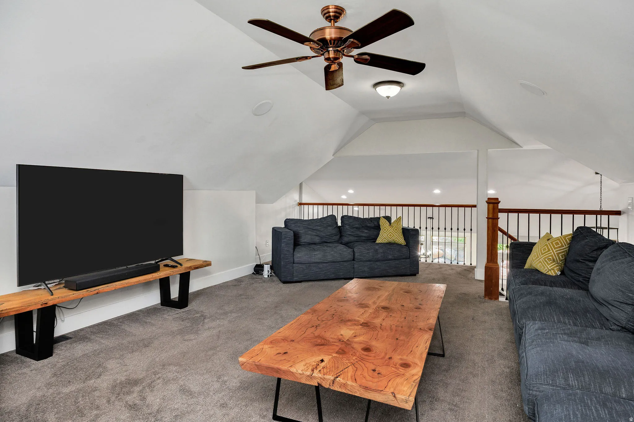 Spacious loft area featuring sloped ceilings, recessed lighting, and a ceiling fan